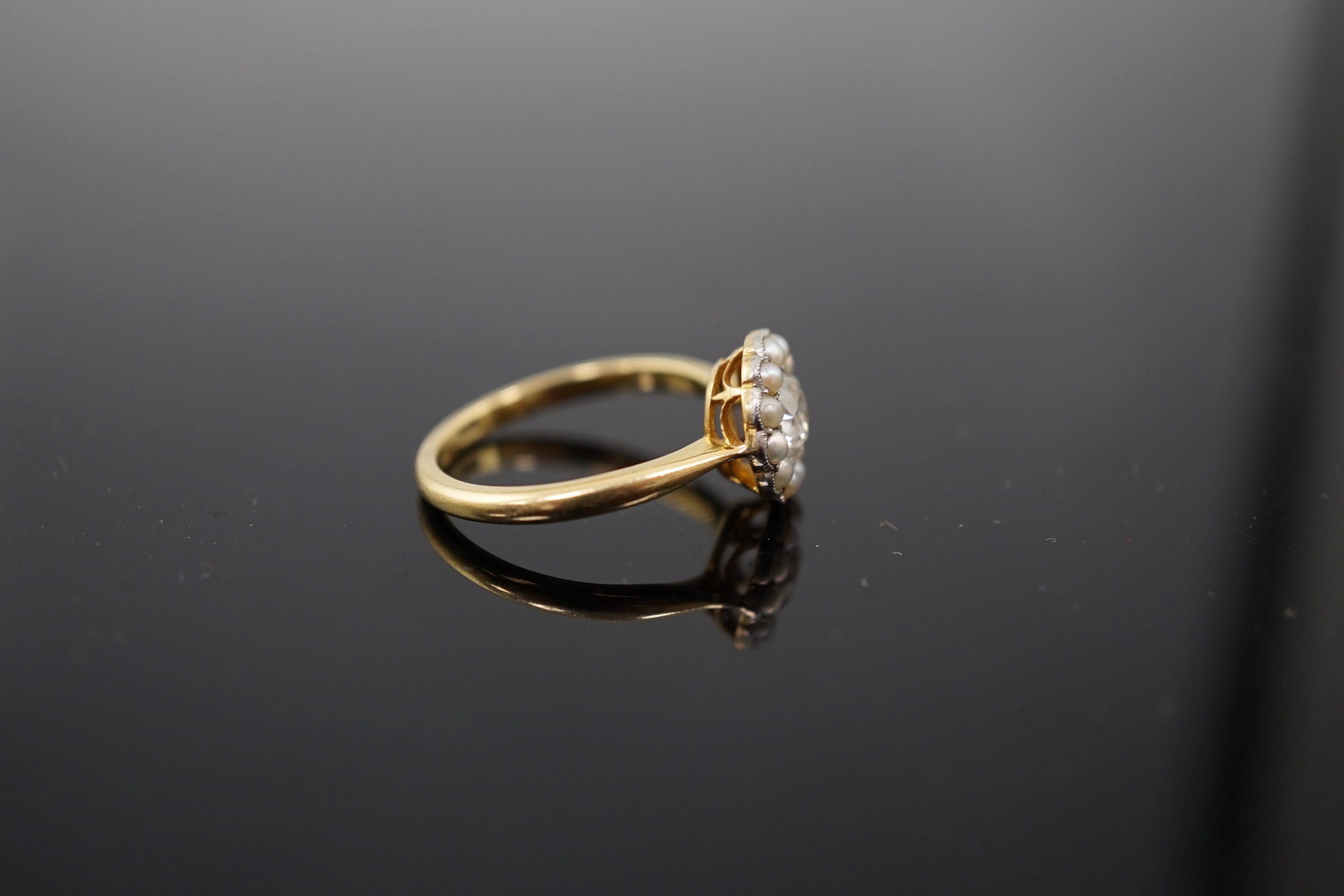An early 20th century 18ct gold, diamond and millegrain set seed pearl circular cluster ring
